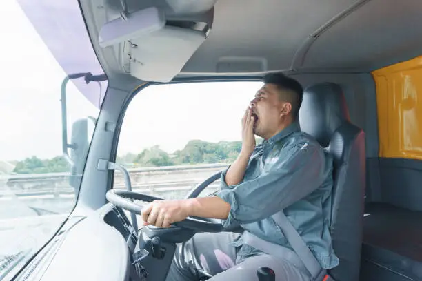 Professional truck driver, adult male, safety belt Yawning and sleepy. Young man worker is confident in the safety of the transport and delivery business for a long time.