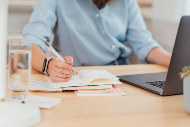 Working from Home: Hand of a Businesswoman Writing Notes