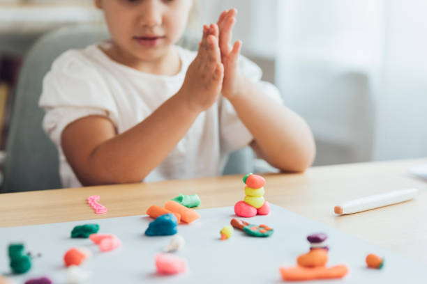 Preschooler Activities: Hands of a Little Girl Playing With Plasticine Making Shapes and Animals, a Close Up Creative kids: an anonymous little girl playing with plasticine at home. preschooler caucasian one person part of stock pictures, royalty-free photos & images