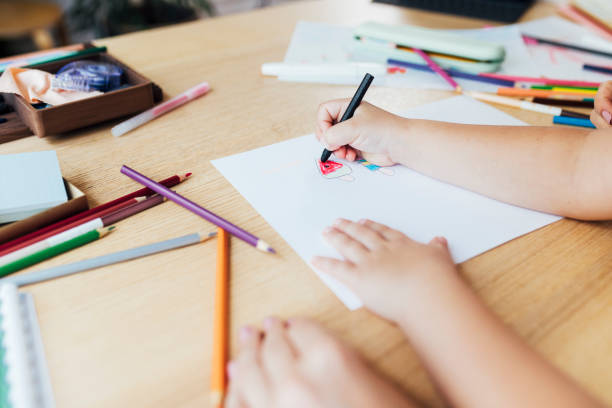 istock Homeschooling: Hands of an Unrecognizable Child Drawing While Sitting on her Mother's Lap, Lockdown Activities Concept 1264365905