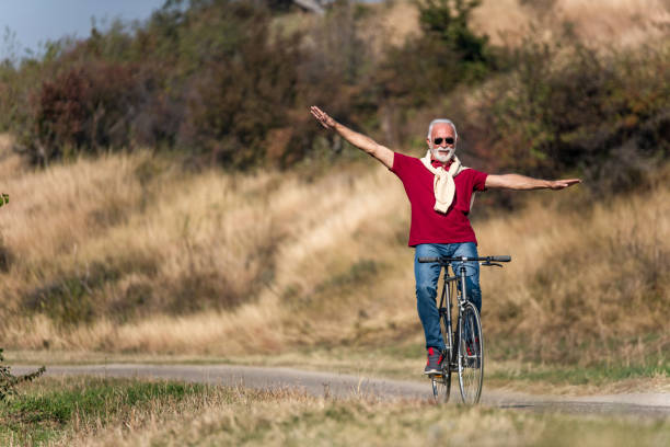 istock Senior man riding a bicycle on a rural road in nature. 1264368950