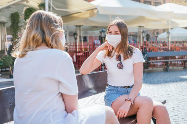 istock Two friends with face masks talking with social distance 1264372645