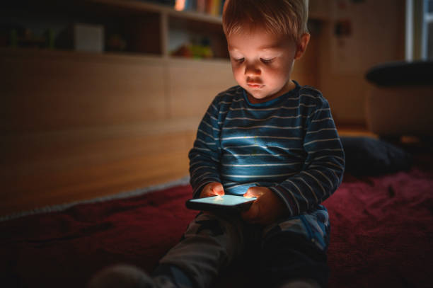 istock Cute boy holding mobile phone and sitting on the floor 1264379045