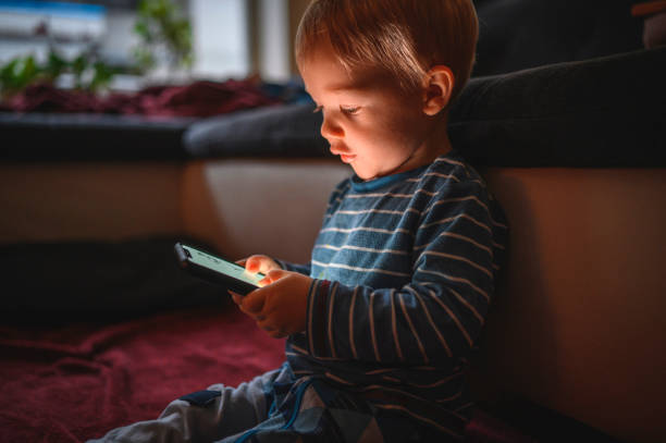 istock Cute boy holding mobile phone and sitting on the floor 1264379048