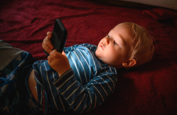 istock Cute boy holding mobile phone and lying on back on the floor 1264379050