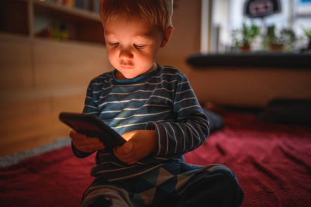 istock Cute boy holding mobile phone and sitting on the floor 1264379051