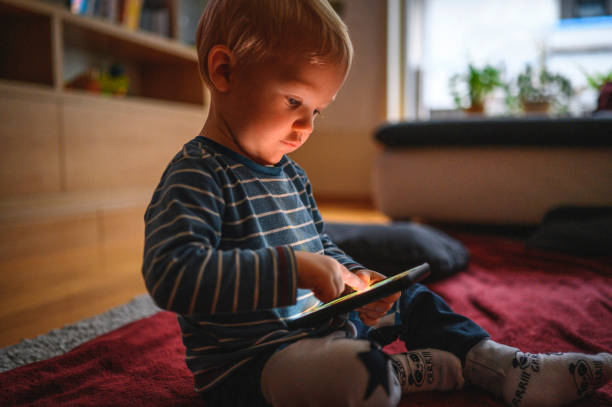istock Cute boy holding mobile phone and sitting on the floor 1264379053
