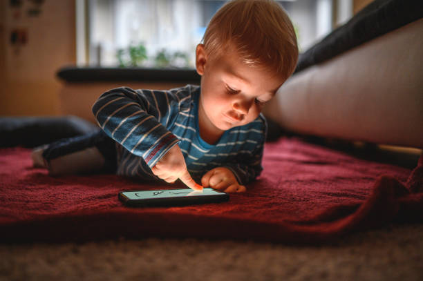 istock Cute boy typing on mobile phone and lying on the floor 1264379056