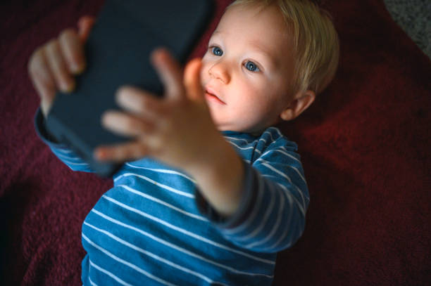 istock Cute boy holding mobile phone and lying on back on the floor 1264379058