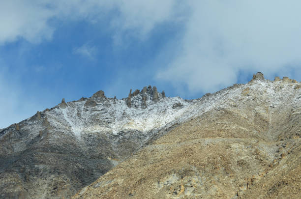 istock Rocky pinnacles on a mountain peak seen against a blue sky with white clouds 1264386030