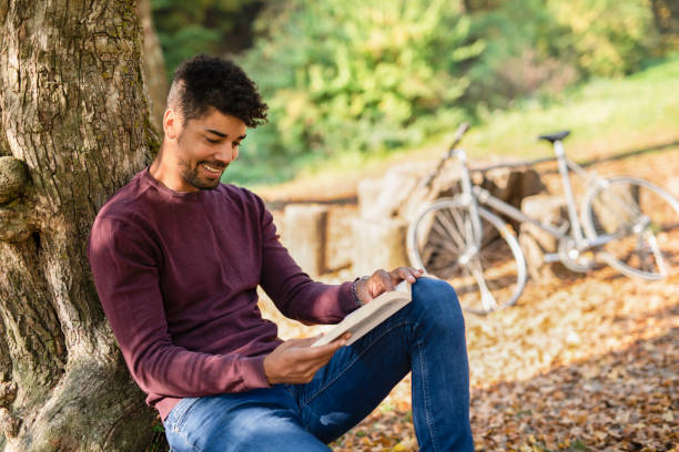 istock Happy young man reading a book in nature. 1264386159