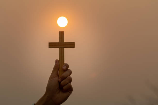 손을 잡고 십자가를 잡고 있습니다. 예수.탄원과 신앙의 상징. 하늘에 햇빛과 십자가의 상징. 텍스트를 입력할 공간이 있습니다. - praying human hand worshipper wood 뉴스 사진 이미지