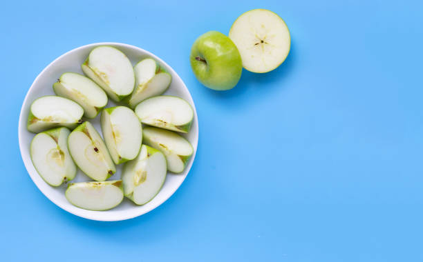 istock Fresh green apple slices on white plate on blue background. 1264403985