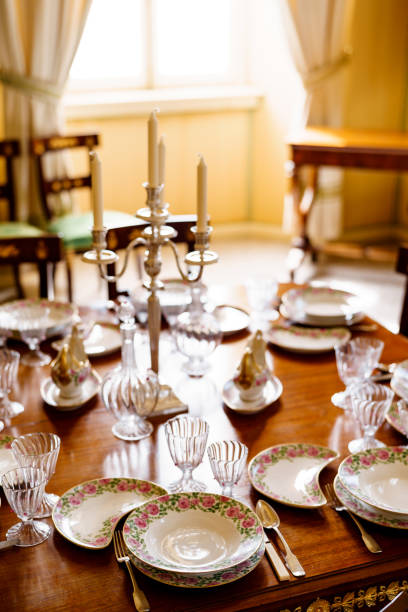 istock Festive table setting with clean empty plates, spoons, knives, wine glasses, decanters and a candlestick in the center on a wooden table in the room. 1264414949