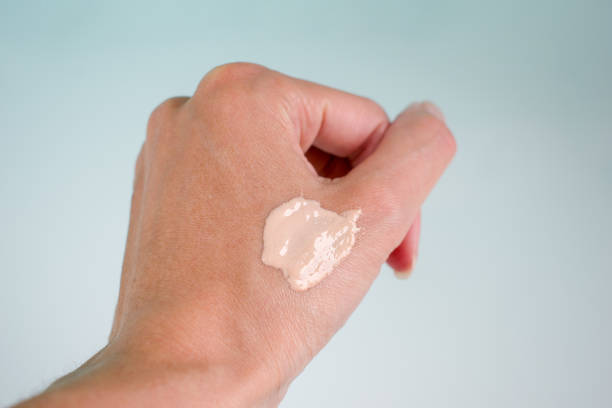 Woman hand with cosmetic foundation or concealer swatches against white background, closeup. Woman hand with cosmetic foundation cream or concealer swatches against light background, closeup. Macro photo. liquid foundation face stock pictures, royalty-free photos & images
