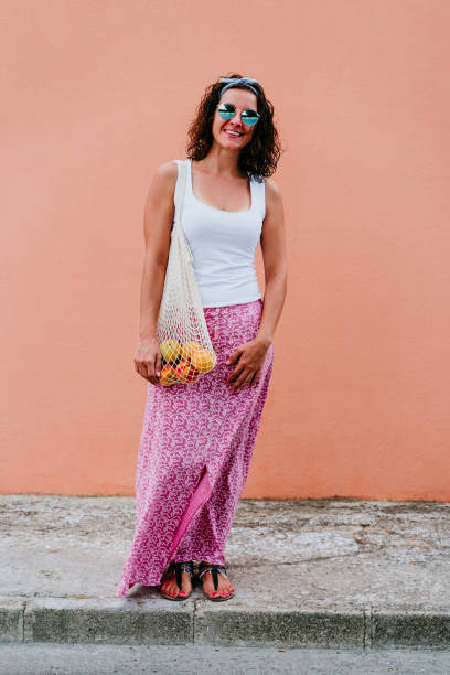 mulher andando pela cidade, segurando um saco de algodão com frutas. conceito de lixo ecológico e zero - earth cheerful orange white - fotografias e filmes do acervo