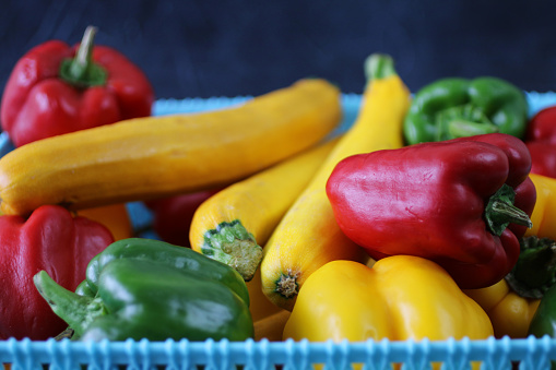 Stock photo showing a close-up view of some freshly picked, ripe fruit and vegetables including courgettes, green, yellow and red peppers.