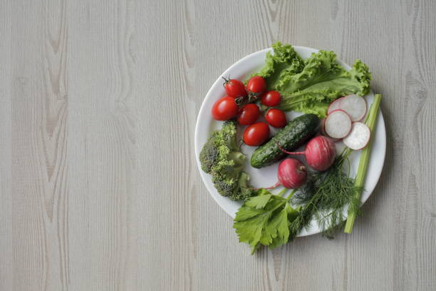 istock Fresh vegetables in a white plate on a light wooden table 1264429978
