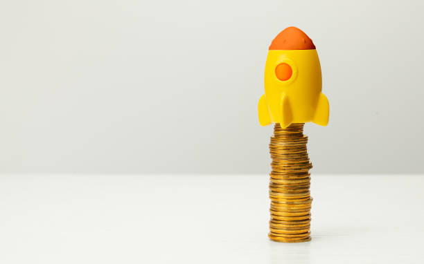 istock Rocket and stack of gold coins on gray background 1264431824