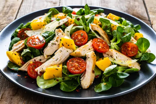 Photo of Caesar salad  - vegetable salad with roast chicken meat on wooden background