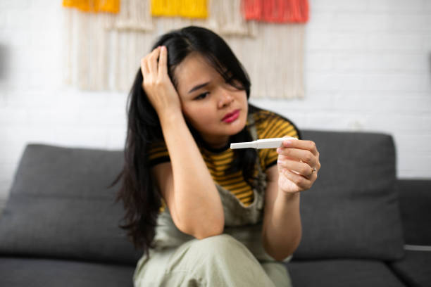 istock Asian young woman looking at pregnancy test with disappointed expression 1264437127