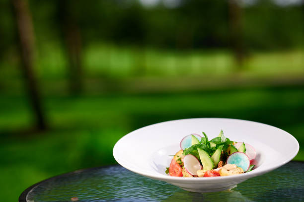 Delicious summer salad with fresh vegetables in a white plate with tomatoes, radishes, avocado, olives