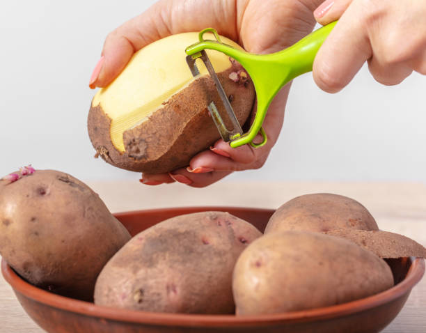 la cuisinière femme nettoie les pommes de terre - raw potato organic human skin food photos et images de collection