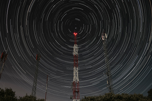 communication antennas on the mountain and circumpolar stars at night. Outdoors.