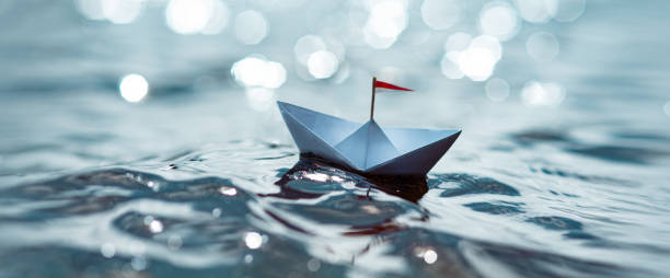 istock Paper boat sailing on sunny sea 1264444077
