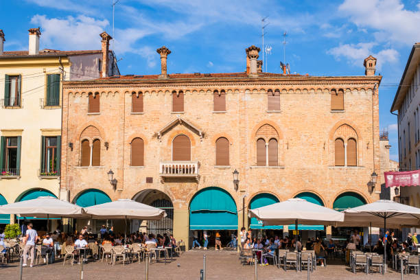 Tourists and locals sitting at the outdoor tables in Piazza Duomo in the historic center of Padua, one of the most important and visited cities in the Veneto region, in northeast Italy.