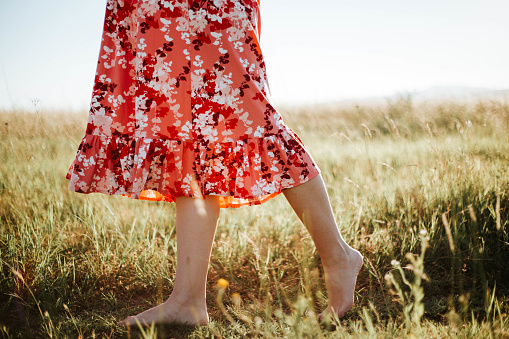 A barefoot woman steps through the grass