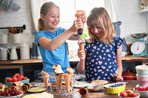 Little Girls Preparing Ice Cream in Cone with Various Toppings, Fruits, and Candy Sprinklers