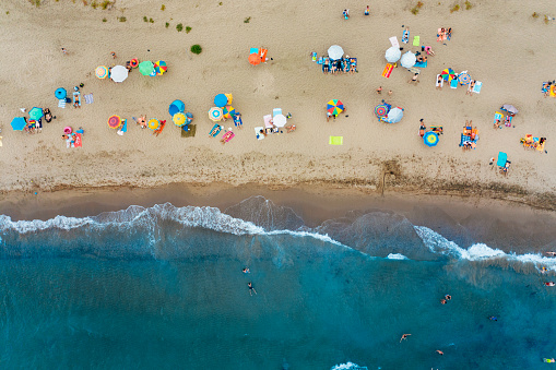 A lot of people are having fun at the beach , plenty of colorful umbrellas and clear sea