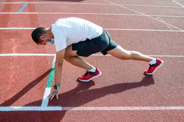 istock Masked runner in the starting block on athletic tracks. Exercise concept covid-19 1264449279