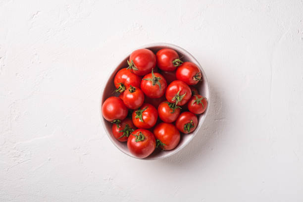 istock Fresh ripe tomatoes in bowl on white concrete background, top view 1264450959