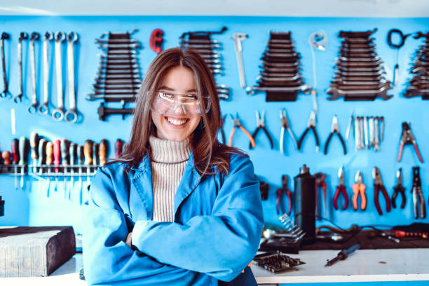 cute female mechanic and her wall of tools - men baseball cap focus determination imagens e fotografias de stock