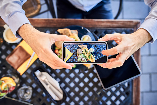 Overhead view of man taking smartphone picture of breakfast in outdoors cafe