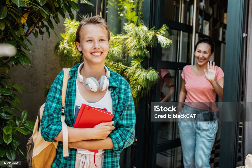 Mother accompanies her teenage daughter to school Asian woman is standing on the front door and daughter is going to school Empathy Stock Photo