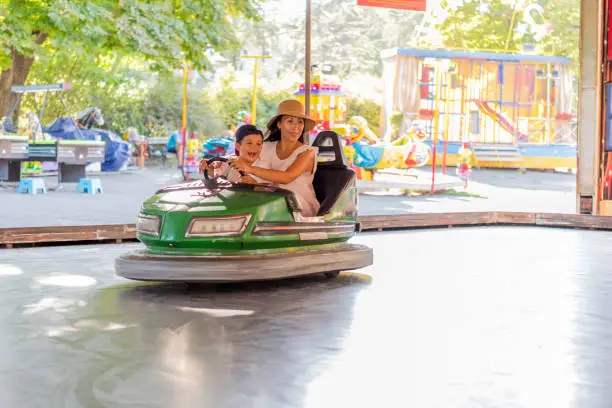 We gonna have fun at amusement park. Mom and young son in a bumper car at an amusement park. Single mother with children, driving bumper cars in amusement park