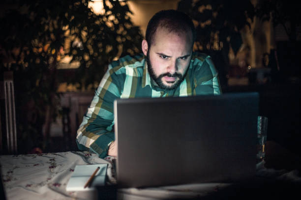 istock Man working and using laptop at home late at night 1264456798