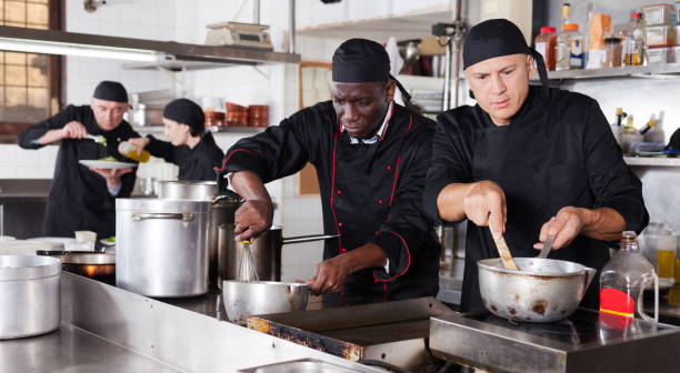 istock Positive cooks in process of working in kitchen of restaurant 1264457413