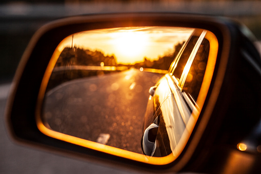Sunset in the exterior mirror of the modern car while driving