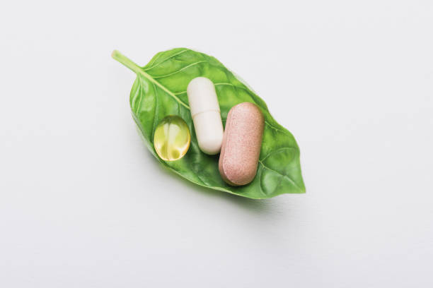 istock pills on green leaf on white background, naturopathy concept 1264459671