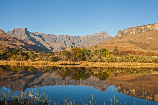 Reflections of the Amphitheater Formation in a calm Drakensberg lake in Royal Natal National Park. KwaZulu-Natal. South Africa
