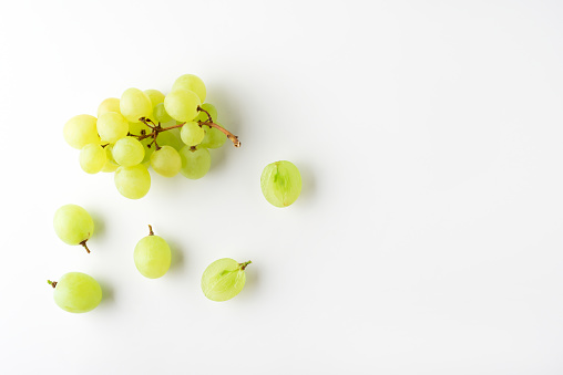 Green grape without leaves on white background. Flat lay. Summer food concept.