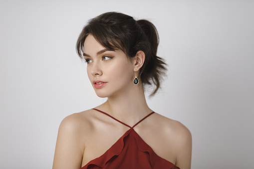 Beauty portrait of female face with natural perfect skin. Studio portrait of a beautiful young woman with brown hair in red dress.