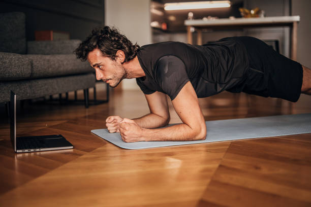 istock Young man taking online yoga lessons at home 1264470158