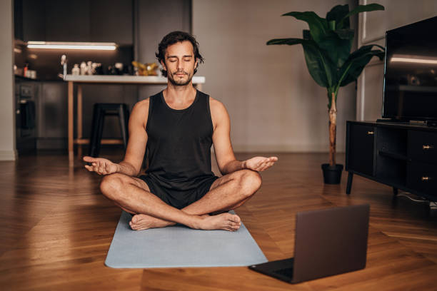 hombre meditando en la sala de estar - meditation fotografías e imágenes de stock