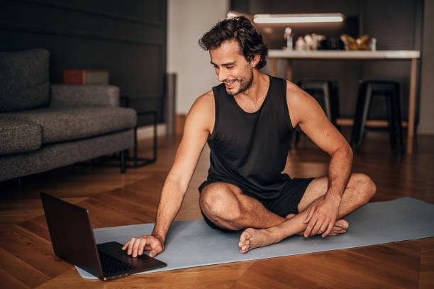 istock Young man taking online yoga lessons at home 1264472232
