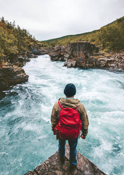 istock Man traveling with backpack enjoying view alone active lifestyle hiking at river canyon adventure vacations outdoor in Sweden 1264472510